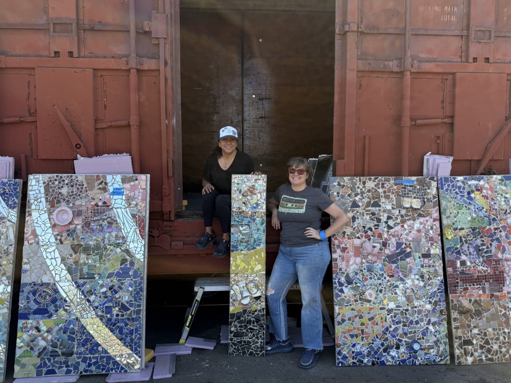 Kristina Young and her "right hand woman" Sandra Cruz-Wilson stand next to the box car that became the new home to the Quake Mosaic, created under Young's direction. Izzi Valencia photo