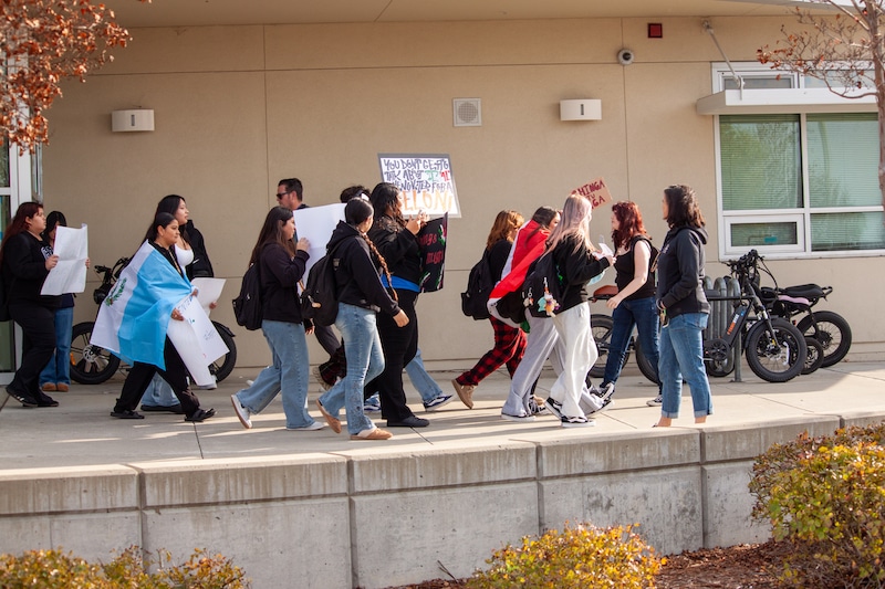 Students walking and holding protest signs outside their school