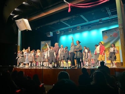 children on stage in costumes dancing and cheering