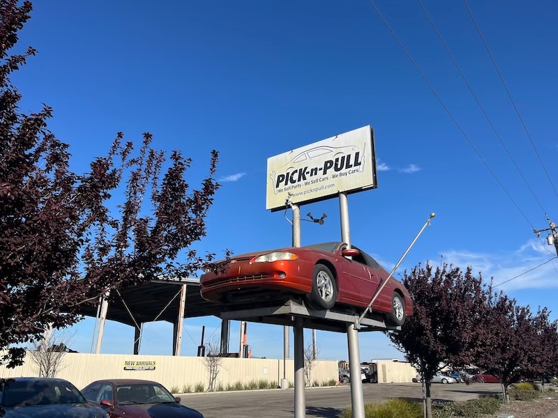 car on a post with a pick-n-pull sign on it