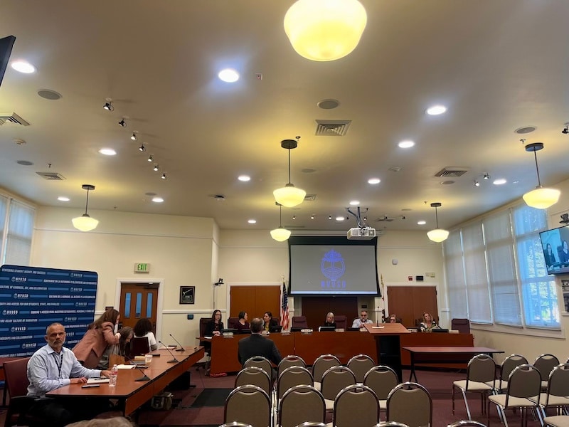 a room filled with empty chairs facing people sitting at tables