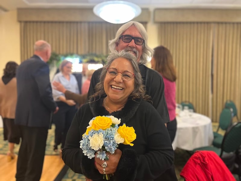 a couple smiling and holding flowers