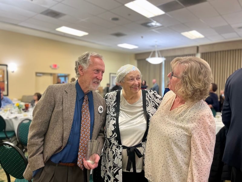 three people standing together talking
